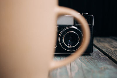 Camera seen through cup handle on table