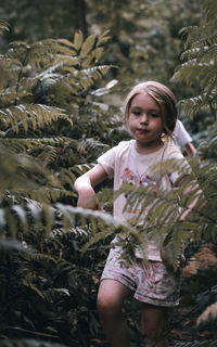 Portrait of smiling young woman standing against plants