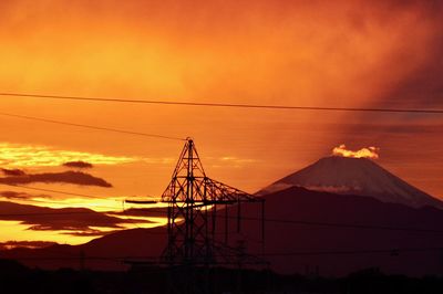 Silhouette cranes against sky during sunset