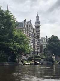 Buildings at waterfront against cloudy sky