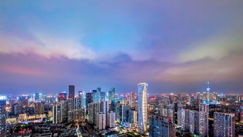 Illuminated modern buildings in city against sky