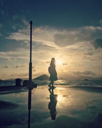 Silhouette man standing on beach against sky during sunset