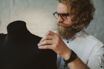 Fashion designer looking mannequin while standing in workshop