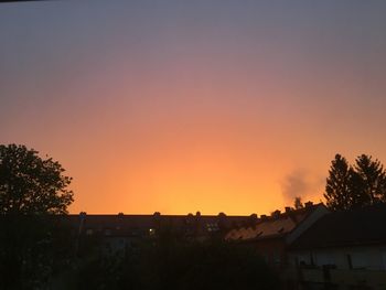 Silhouette trees and buildings against sky during sunset