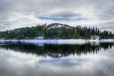 Reflection of trees and mountains in lake against cloudy sky