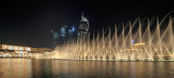 Illuminated buildings by river at night