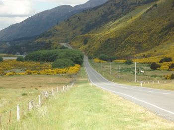 Scenic view of road amidst field against sky