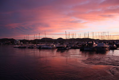 Boats moored in harbor during sunset