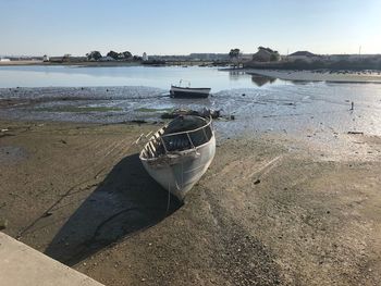 Boat moored on beach against sky