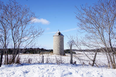 Bare trees on snow covered land against sky