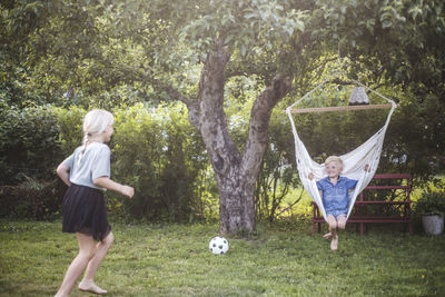 Children playing soccer on field against trees