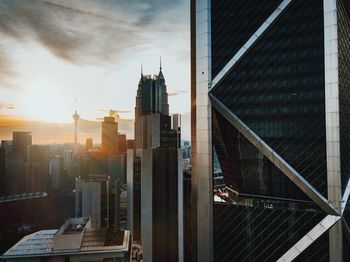 Modern buildings in city against sky during sunset