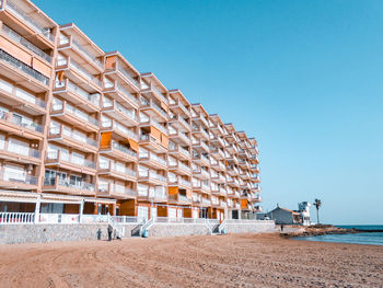 View of building by beach against clear blue sky
