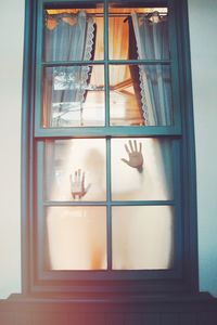 Hands on glass window of house