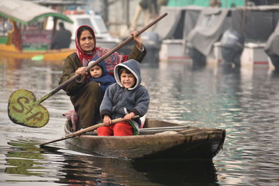 Woman with children oaring canoe on lake during winter