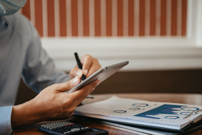 Midsection of man holding paper with text on table