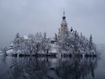 Lake by building against sky during winter