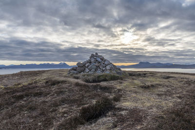 Rocks on field against cloudy sky