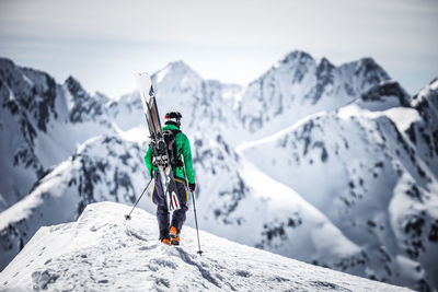 Person standing on snowcapped mountain against sky