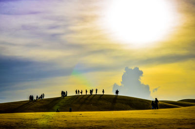 People on landscape against cloudy sky