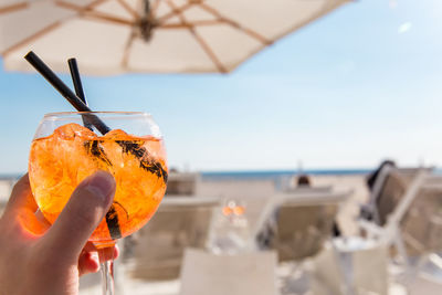 Close-up of hand holding drink at beach