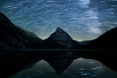 Scenic view of lake and mountains against sky at night