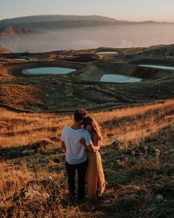 Rear view of couple kissing on field