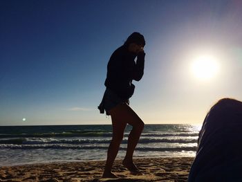 Man standing on beach against sky during sunset