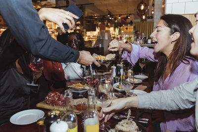 Cropped image of waiter serving food and drinks to customers at table