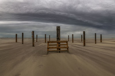 Wooden posts on beach against sky