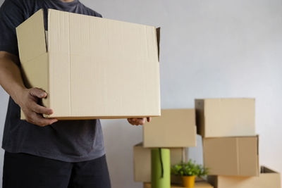 Midsection of man holding paper while standing against wall