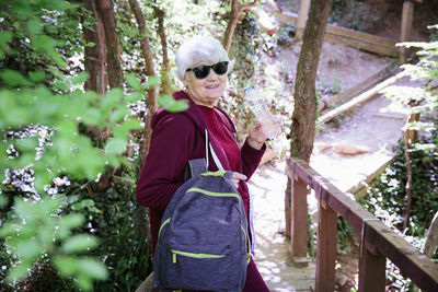 Mature female spending vacations outdoors, walking in forest with rucksack