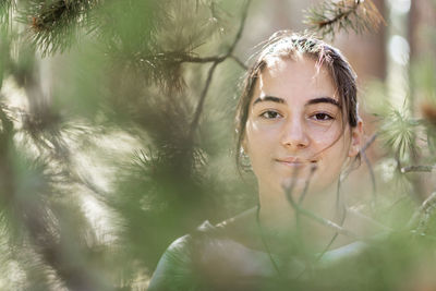 Portrait of smiling young woman by plants outdoors