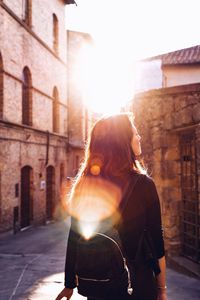 Rear view of woman standing on street amidst buildings