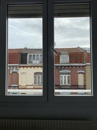 Buildings against sky seen through glass window