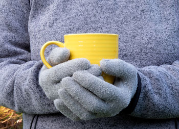 Midsection of men holding yellow cup