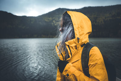 Woman standing by lake against mountain