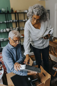 Female owner analyzing box held by male colleague in antique shop