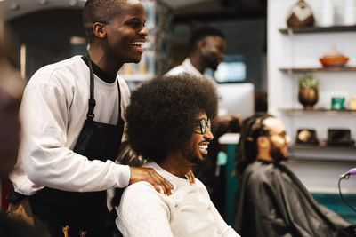 Happy male hairdresser talking with customer in barber shop