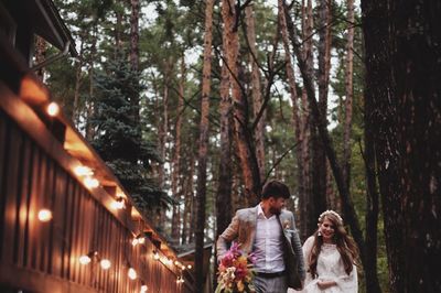 Wedding couple running by trees