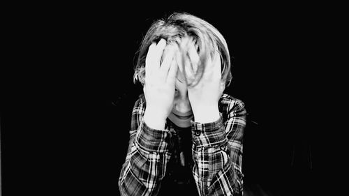 Close-up of boy against black background