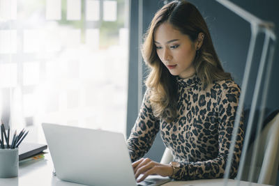 Businesswoman using laptop while sitting in office