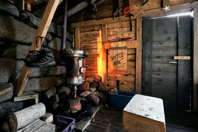 Inside view of a wooden hiking cabin with an old wood oven and hiking gear