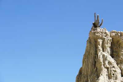 Low angle view of clear blue sky and cliff