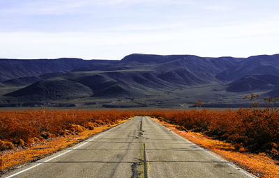 Road leading towards mountains against sky