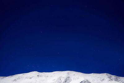 Low angle view of snow landscape against blue sky