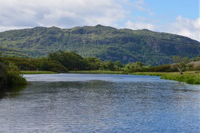 Scenic view of lake by mountains against sky