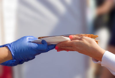 Close-up of woman holding food in hands against white wall
