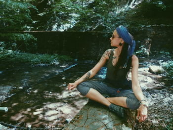 Young woman sitting on rock in forest