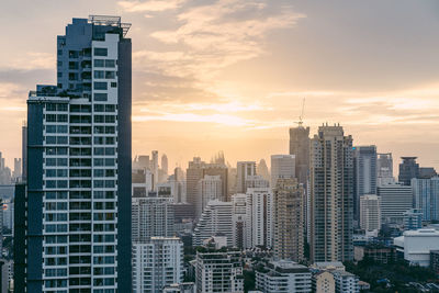 Modern buildings in city against sky during sunset